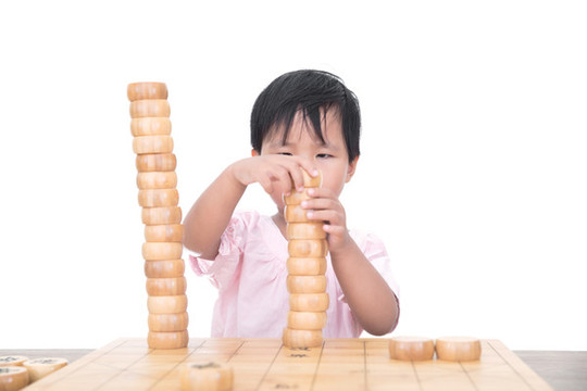 小女孩桌子上摞中國(guó)象棋棋子
