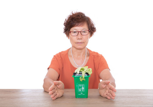 雙手呵護著綠色的廚余垃圾桶和菜