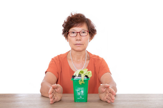 雙手呵護著綠色的廚余垃圾桶和菜