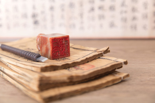 泛黃的書籍其上一枚印章和刻刀