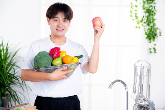 男人在廚房抱蔬菜水果