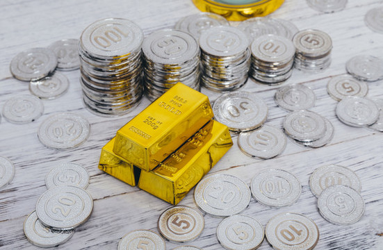 白色背景下放著的硬幣和金塊