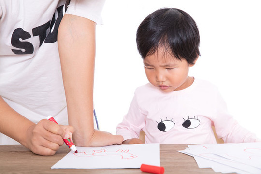 老師在認(rèn)真的輔導(dǎo)小女孩畫畫