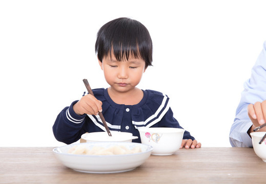 中國小女孩坐在桌子前吃餃子