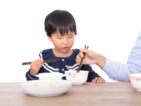 中國小女孩坐在桌子前吃餃子