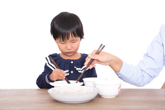媽媽在幫助自己的女兒吃餃子