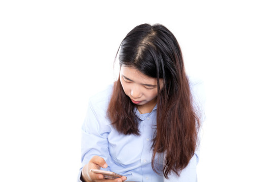 白背景前長(zhǎng)發(fā)女孩在低頭玩手機(jī)