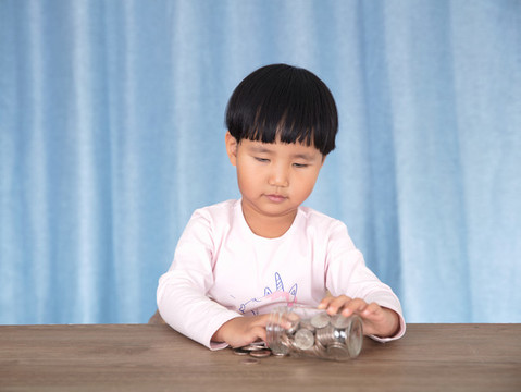 亞洲小女孩在玩耍玻璃瓶里的美元