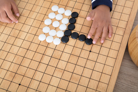 小孩子在棋盤上學(xué)習(xí)下圍棋