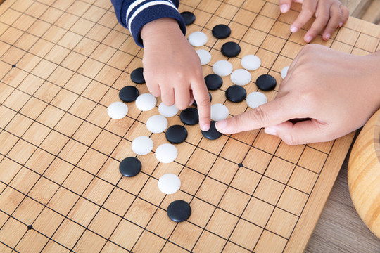 大人的手指導(dǎo)著小孩的手下圍棋