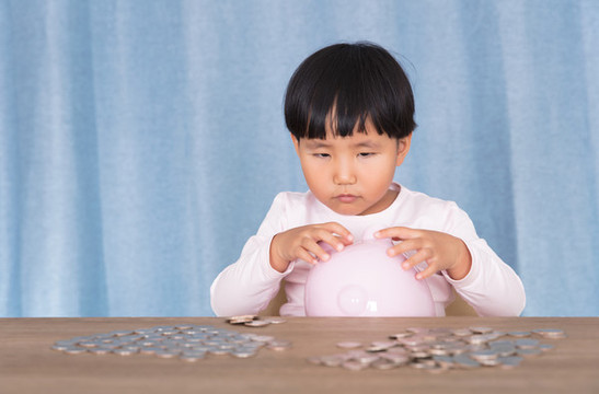 小孩子在擺弄手中的小豬存錢罐
