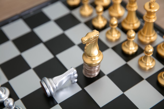站在硬幣上的金色馬棋子下跪