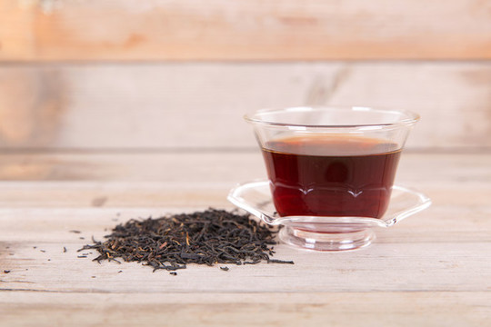 一碗泡好的紅茶飲品和一堆茶葉
