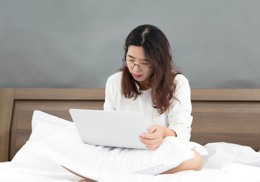 坐在床上使用電腦的中國女士