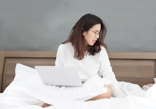 坐在床上使用電腦的中國(guó)女士