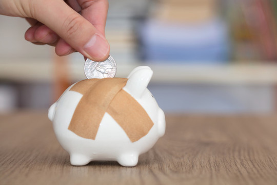 硬幣放入貼著創(chuàng)可貼的存錢罐里