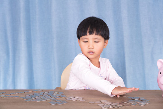 小女孩在擺弄桌子上的美元硬幣