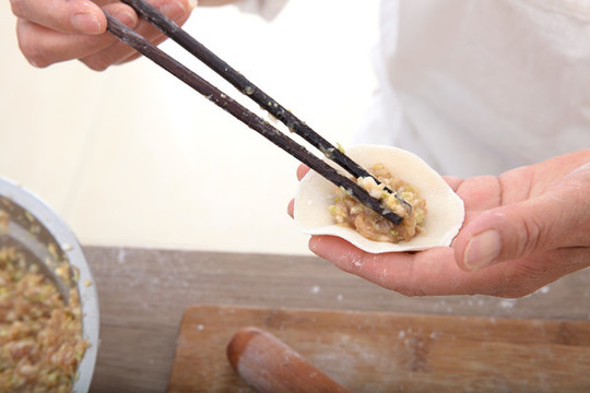 筷子夾著肉餡放進餃子皮里包餃子