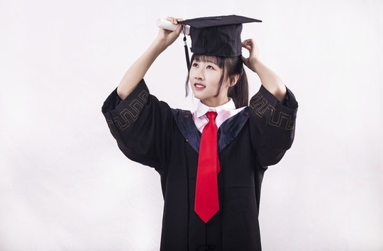 純色背景下穿著學(xué)士服的女孩