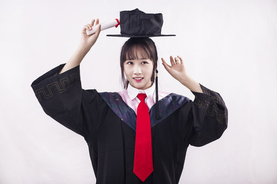 純色背景下穿著學(xué)士服的女孩