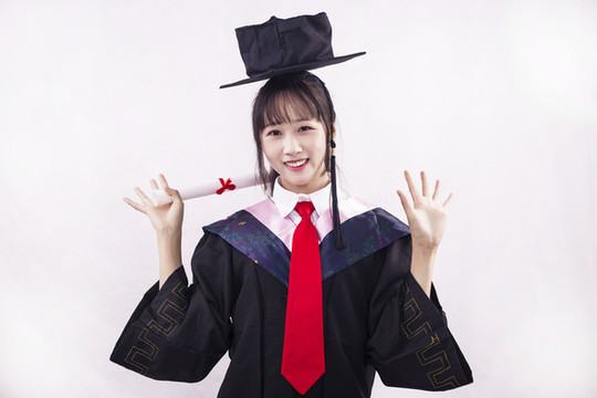 純色背景下穿著學(xué)士服的女孩