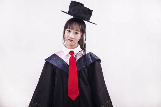 純色背景下穿著學(xué)士服的女孩