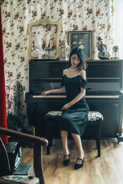 室內(nèi)穿著黑色連衣裙彈鋼琴的女孩
