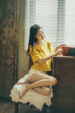 窗戶邊坐著的穿著黃色短袖的女孩