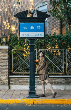 路牌下捧著花束的女孩