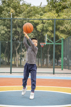 學(xué)校操場上打籃球的小男孩