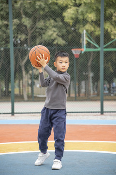學(xué)校操場上打籃球的小男孩