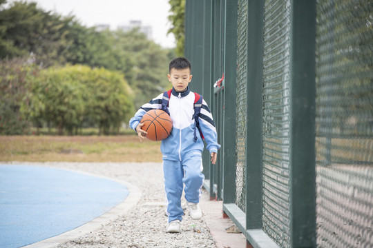 操場上抱著籃球的小學(xué)生