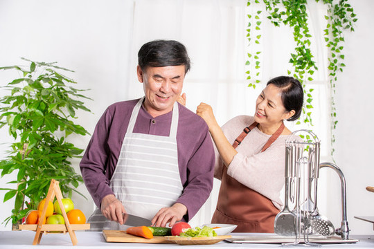 老年夫妻在廚房做飯捶肩