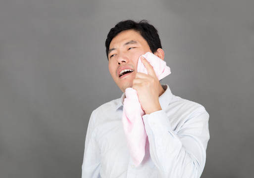 牙痛的男士用毛巾熱敷臉部