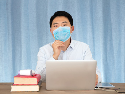 工位上戴著一次性口罩的男士
