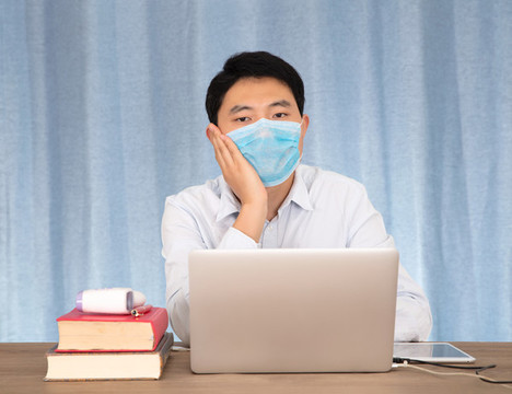 工位上戴著一次性口罩的男士