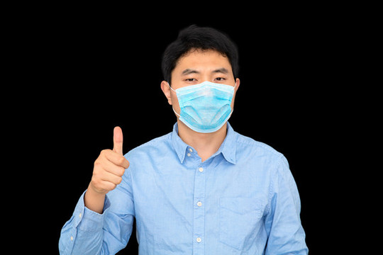 豎著大拇指站在黑背景前的男士