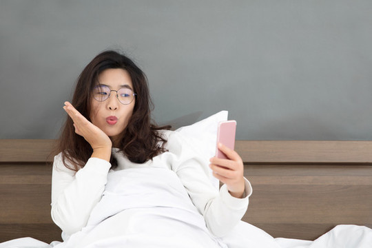 女子玩手機坐在床上