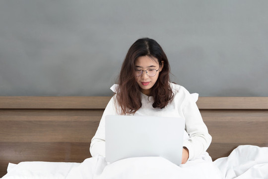 坐在床上使用電腦的中國女士