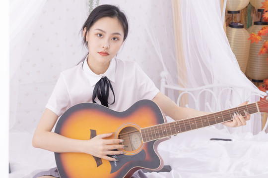 室內(nèi)女性在床上彈吉他