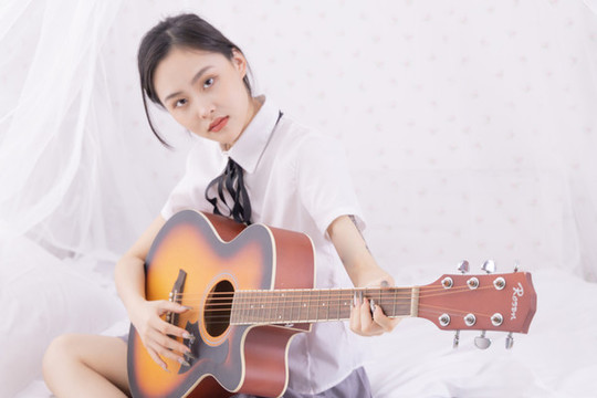 室內(nèi)女性在床上彈吉他