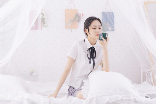 亞洲女性坐在床上拿著杯子