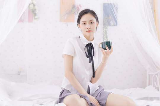 亞洲女性坐在床上拿著杯子
