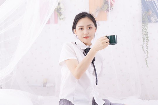 亞洲女性坐在床上拿著杯子