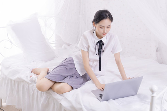 女孩在床上使用筆記本電腦