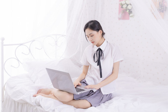 女孩在床上使用筆記本電腦