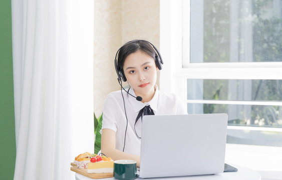 女性客服戴著耳麥?zhǔn)褂秒娔X