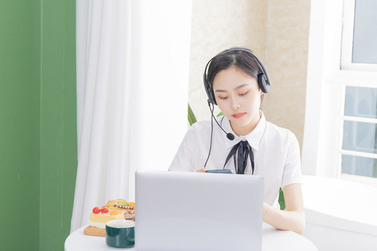 女性客服戴著耳麥?zhǔn)褂秒娔X
