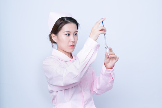 年輕女醫(yī)護人員手持注射器