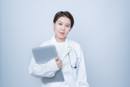 抱著筆記本電腦的白大褂女性
